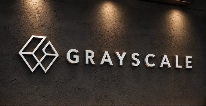 The Grayscale logo, featuring a stylized geometric 'G' emblem next to the company name in white, displayed on a textured dark wall.