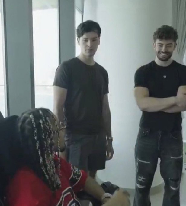 A woman with braided hair sits in a chair while two men stand behind her smiling, illustrating the playful scenario of friends reacting to the unexpected sight of selling on side wallets.