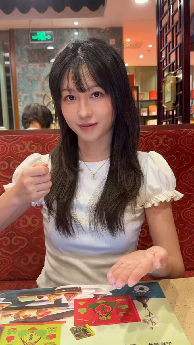 The image features a young woman sitting at a table, holding up her hand with both hands as if she's about to give something or make a wish. The background of the photo shows a dining area with a red booth seat where the girl is seated. There are also several other people in the scene, but they are not the main focus of the image.

The post includes an image of a gift box from Binance, which has been edited to include a cartoon character and a message about children's day on June 1st. The caption reads "The popular transition on IG See what gift I can conjure up Wishing all big and little friends a happy Children'S Day on June 1st! Thanks to Binance' s gift box @binancezh".