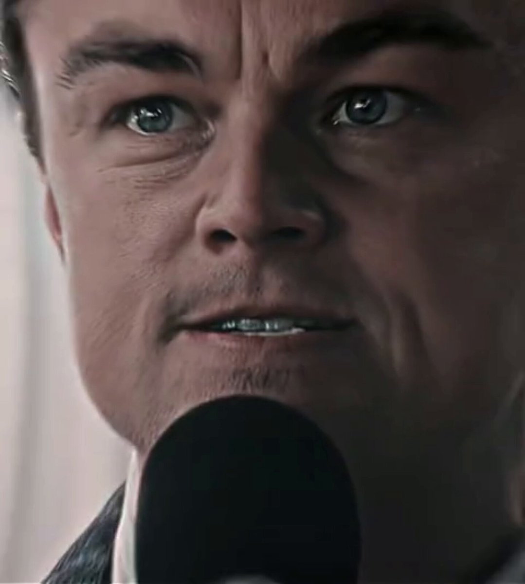 The image features a close-up of a man's face, with his eyes looking off into the distance as he speaks into a microphone. The background appears to be a blurred room or space, which could be a recording studio or an event venue. The focus on the man and his facial expressions suggests that this is likely a speech or presentation being delivered at an event or gathering.