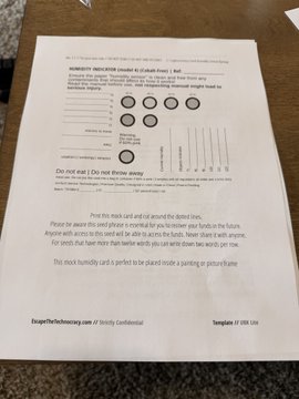 A homework checklist titled "HOMEWORK INDICATOR (model ID: CLASS-44xi) | Test" sits on a wooden table, featuring circular indicators, answer fields, and instructions to verify the severity and legs of a donation. The handwritten note at the bottom reads "This stack humidity card is perfect to be placed inside a pumice jar or polycarbonate," aligning with the user's caption about switching from a Coldcard to a Trezor hardware wallet.