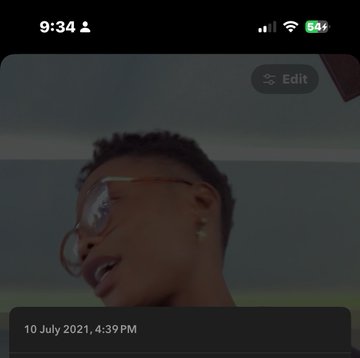A young man with short hair and round glasses looks upward against a moody, dark sky, captured mid-expression with his mouth slightly open. The timestamp "10 July 2021, 4:39 PM" marks this as his very first video, contrasting his humble beginnings as a student promoting Forsage with his growth as a content creator by 2026.