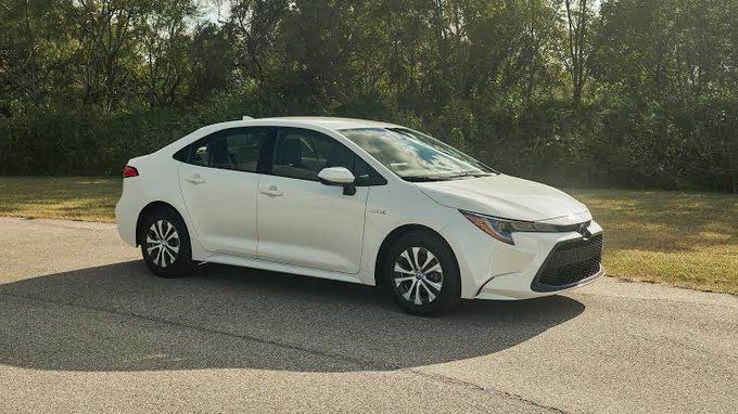 A white 2020 Toyota Corolla sedan is parked on a paved area with trees in the background. The image illustrates the post's narrative of using cryptocurrency profits to purchase a first car for gig economy work.