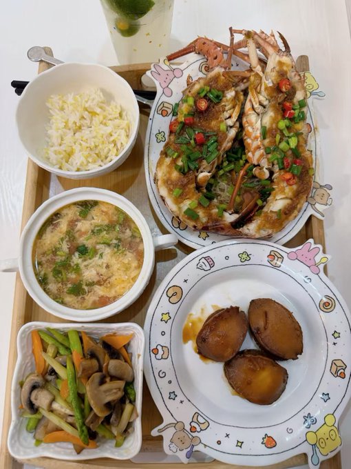 The image shows a meal tray featuring a large plate of garlic and chili crab, a bowl of white rice, a cup of tomato egg drop soup, a side of stir-fried mixed vegetables with mushrooms, and a small plate of braised abalone, with a cold green beverage in the background. The caption ties into the post by suggesting that a seafood feast pairing crab with tomato egg drop soup is the perfect comfort meal to solve any problem.
