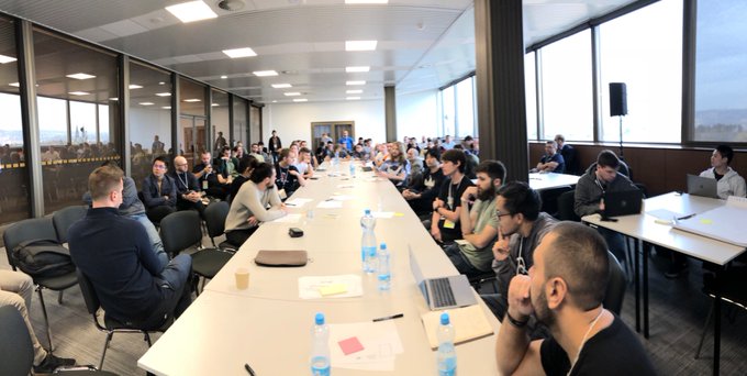 A group of people sit around a long conference table in a modern office space, engaged in what appears to be a roundtable discussion. The post connects this image to a 2018 Prague meetup about meta-transactions, noting the speaker's previous company tried to improve login UX before account abstraction existed.