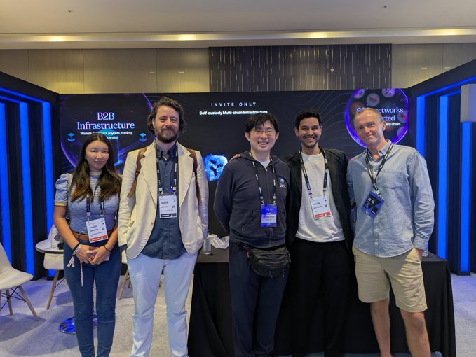 Five people pose together at an invite-only event, with backdrop text reading "B2B Infrastructure" and "Self-custody Multi-chain Infrastructure" on the left, and "Networks" on the right, as the attendees—wearing branded lanyards—appear to be networking around JPYC (a Japanese yen stablecoin) integration. The post mentions a Tria card users capable of using JPYC, suggesting this gathering involves the team or partners behind that payment integration.