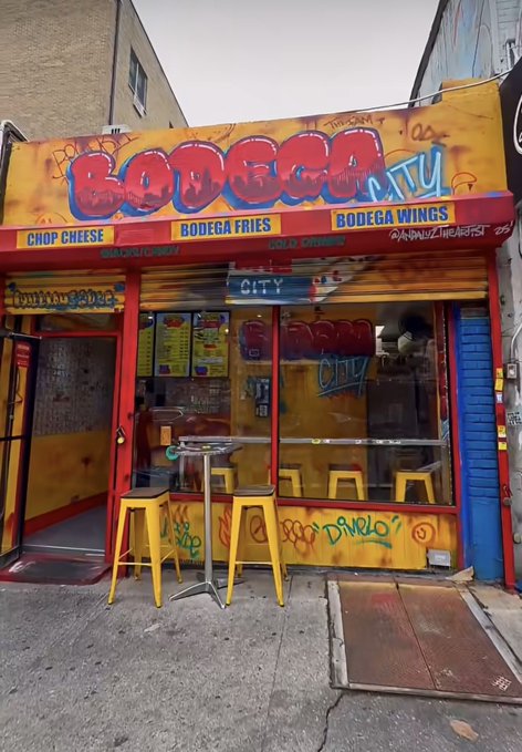 The image shows the storefront of "BODEGA CITY," a small shop with a vibrant orange and yellow graffiti-style sign advertising Chop Cheese, Bodega Fries, and Bodega Wings. The accompanying post promotes a community NFT holder perk at the "BODEGA CITY" location in Brooklyn at 139 Havemeyer St, where NYC-area holders can claim a free Chopped Cheese.