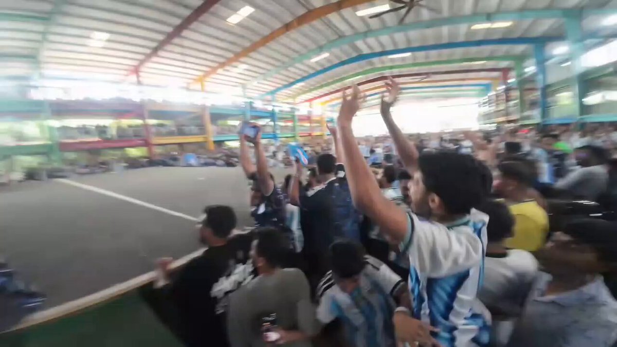 The image shows a group of people gathered together, with some of them holding up their arms as if they are cheering for a soccer team or celebrating an achievement. The crowd appears to be engaged and excited about something happening within the stadium. There is also a person wearing a backpack in the scene. The post seems to be related to a coin called "LUNC", which could possibly be associated with a sports event, such as the World Cup. The image captures the energy of the moment and the enthusiasm of the fans for their team or the event they are attending.