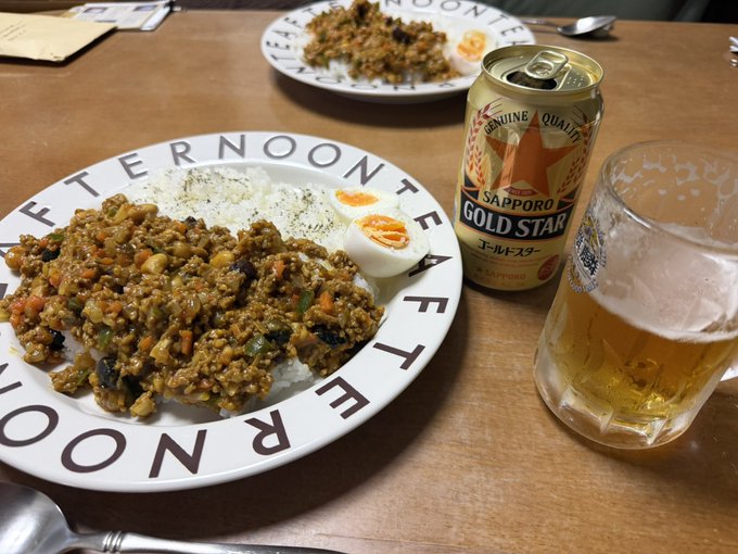 A meal featuring rice topped with keema-style curry and sliced boiled egg on a plate marked 'AFTERNOON TEA', served alongside a can of Sapporo Gold Star beer and a glass of the golden brew.