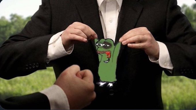 A person in a black suit tears open their white shirt to reveal the green Pepe the Frog character drawn on their chest.
