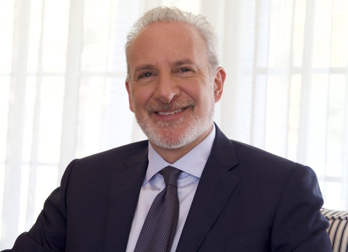 The image features a man wearing a suit, tie, and smiling for the camera. The background includes a window with white blinds that allow natural light into the room. There are no other people or objects visible in the photo.