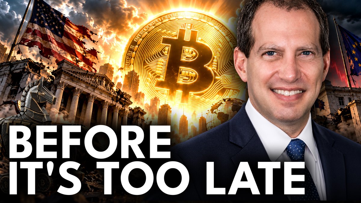 A man in a suit smiles beside a glowing Bitcoin logo and imagery of the US flag and financial buildings, with text reading 'BEFORE IT'S TOO LATE'.