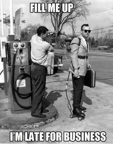 A black and white vintage photograph shows a man in a suit being 'filled up' by a gas station attendant, with the caption 'FILL ME UP / I'M LATE FOR BUSINESS'.