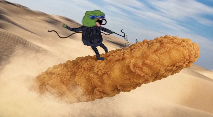 A digitally edited image showing a cartoon frog wearing goggles and a black outfit riding a large fried chicken drumstick as if it were a rocket, flying through a sandy desert landscape.
