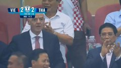 Two men in suits react during what appears to be a sports broadcast, with a scoreboard showing 'VIE 2 - 2 THA'.