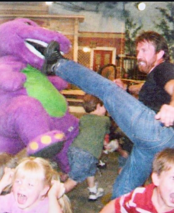 A vintage-style photograph showing a man kicking a Barney the Dinosaur mascot in the face at what looks like a Chuck E. Cheese, while children watch and scream.