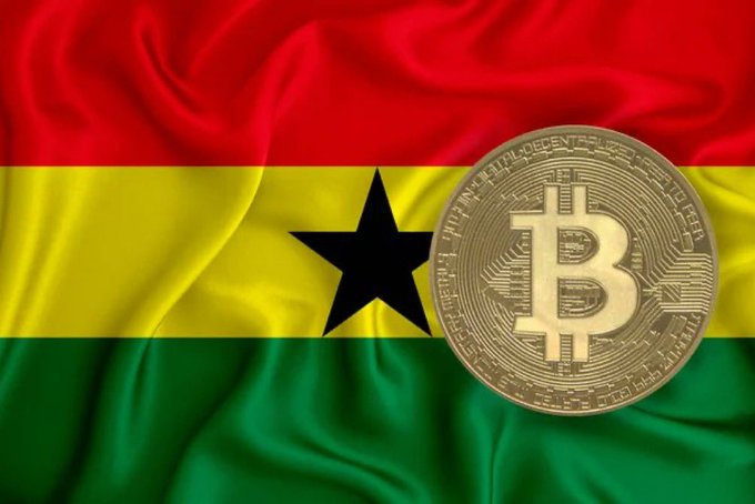 A golden Bitcoin coin rests atop Ghana's flag (red, yellow, and green horizontal stripes with a black star), symbolizing the Bank of Ghana's preparation of new guidelines to support crypto businesses as global cryptocurrency adoption accelerates.