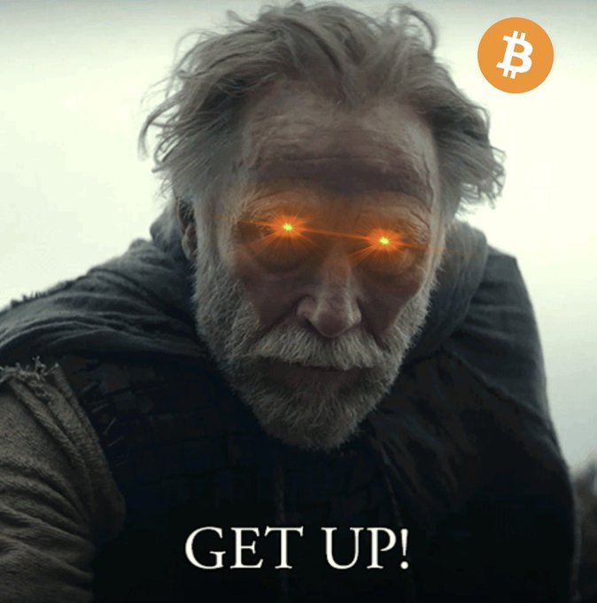 A dramatic meme featuring an older bearded man with glowing red eyes, captioned "GET UP!" with a Bitcoin (₿) logo in the top right corner.