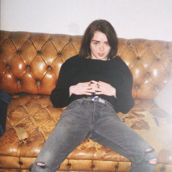 A person with dark hair and red lipstick sits casually on a tufted brown leather couch, wearing a black sweater and ripped jeans, posing with hands clasped. The image doesn't contain any visible text or relate directly to a giveaway post—it appears to be a personal photo shared in a community context rather than promotional material.