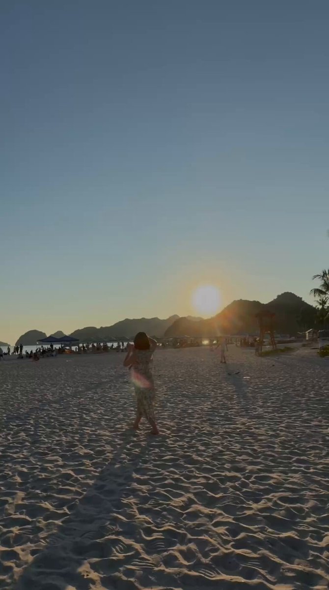 The image shows a woman walking along a sandy beach, with the sun setting behind her. She appears to be enjoying her time at the beach as she walks towards the water. The photo has been edited to include text that reads "Happy new day" and "@wallchain @quipnetwork". This suggests that someone has taken the image and added these elements to create a more engaging or personalized caption for it, possibly to share on social media platforms.

The beach setting is complemented by several umbrellas scattered around in the background, indicating that this location is likely popular among tourists during sunny days. The woman's presence at the beach adds a sense of liveliness and enjoyment to the scene as she walks along the shoreline with the sun setting behind her.