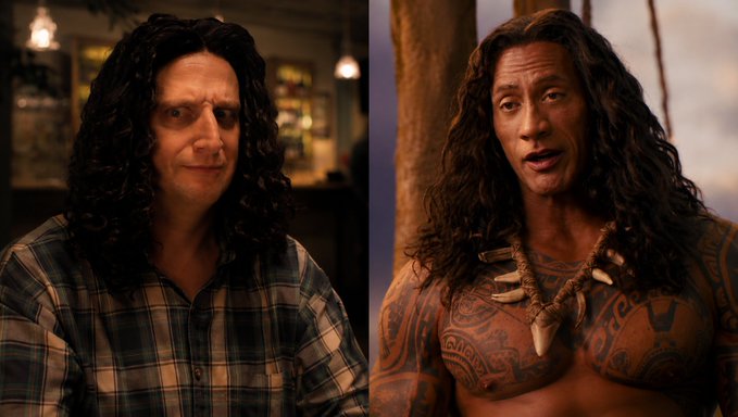 The image shows two men, one wearing a plaid shirt and the other with long hair, sitting next to each other at a table. The man with long hair appears to be wearing a wig or fake hair accessory, while the other man has tattoos on his chest. Both of them are looking off into the distance, seemingly lost in thought.