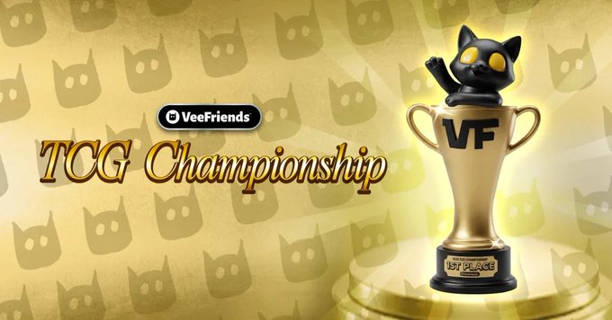 The image features a promotional graphic for the "VeeFriends TCG Championship," displaying a black cat figurine wearing "VF" overalls sitting atop a gold trophy marked "1st Place," set against a gold background with cat silhouettes. The caption "We are LIVE at the 2026 VeeFriends TCG Championship in NYC!" aligns with the image's celebratory, championship-themed visual design.