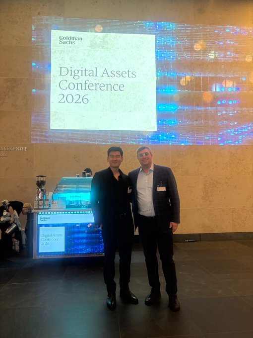 Two men pose in front of a "Goldman Sachs Digital Assets Conference 2026" projection at the event, representing Arbitrum's participation alongside Goldman Sachs and Offchain in discussions with institutional allocators about the Arbitrum Platform's role in the programmable economy.