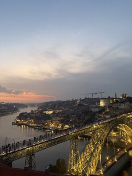 The image shows a beautiful cityscape at night, with a bridge spanning across a river that serves as a prominent feature. The sky above has a mix of clouds and stars, creating an enchanting atmosphere. In the foreground, there are several people walking on the bridge or near it, enjoying their time in the city during the evening hours. 

The post features a photo of Porto, Portugal at night with a view from atop a bridge over the water. The image also includes some text that reads "Night in Porto #porto Are you all enjoying your holiday break well? I've come to Porto for a trip! Even today, with crypto profits I put some Tether into Tria via @useTria And I'm making good use of it while grabbing the reverse drop and cashback Not much funds". The combination of the captivating cityscape and the nighttime atmosphere make this image an appealing visual treat.