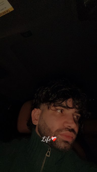 A dimly lit selfie shows a young man with curly hair and a beard inside a car, with a "Life" text and heart emoji overlay, alongside a partially visible "AMBULANCE" sticker in the corner. The image appears to be unrelated to the giveaway post, serving simply as a personal profile-style photo attached to the $SOL giveaway announcement.