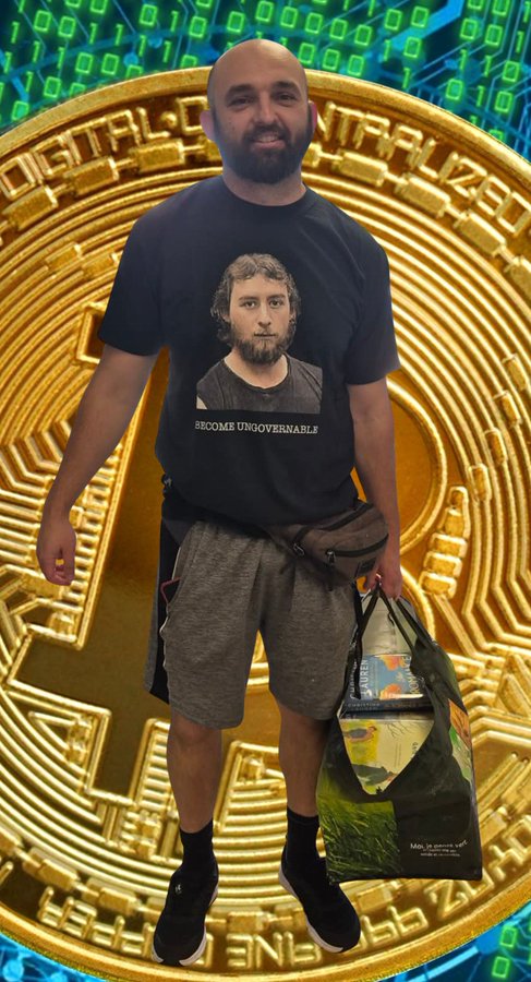 A bearded man stands proudly in front of a large golden Bitcoin emblem, wearing a t-shirt featuring a portrait and the phrase "BECOME UNGOVERNABLE," while holding a reusable shopping bag, embodying the post's message of reclaiming control through Bitcoin.