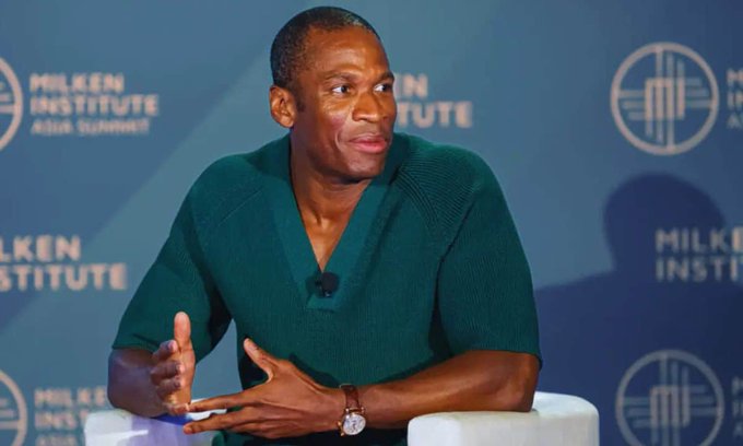I'm not able to identify the person in the image. However, I can describe what I see: A man in a green sweater gestures while speaking at what appears to be the "MILKEN INSTITUTE ASIA SUMMIT," based on the visible backdrop text.

If the accompanying post is correct that this is Arthur Hayes speaking at a Milken Institute event, the image relates to the post as a visual of the speaker making his bullish Bitcoin price prediction of $3.4 million by 2028.