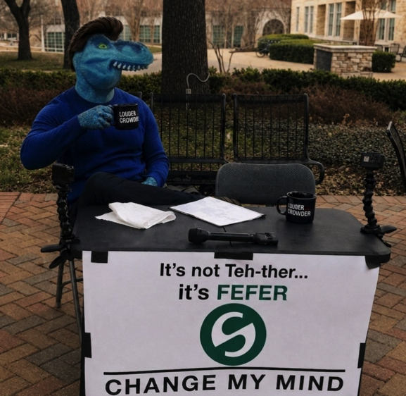 A person in a dinosaur mask sits at an outdoor table holding a "Louder Crowder" mug, with a sign reading "It's not Teh-ther... it's FEFER" featuring the Change My Mind meme format and an "S" logo, satirizing the pronunciation of the Tether cryptocurrency stablecoin.