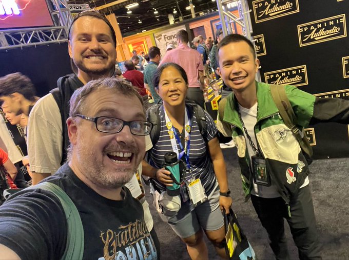 Four people pose together for a group selfie at what appears to be a convention, with a 'PANINI Authentic' banner visible in the background.