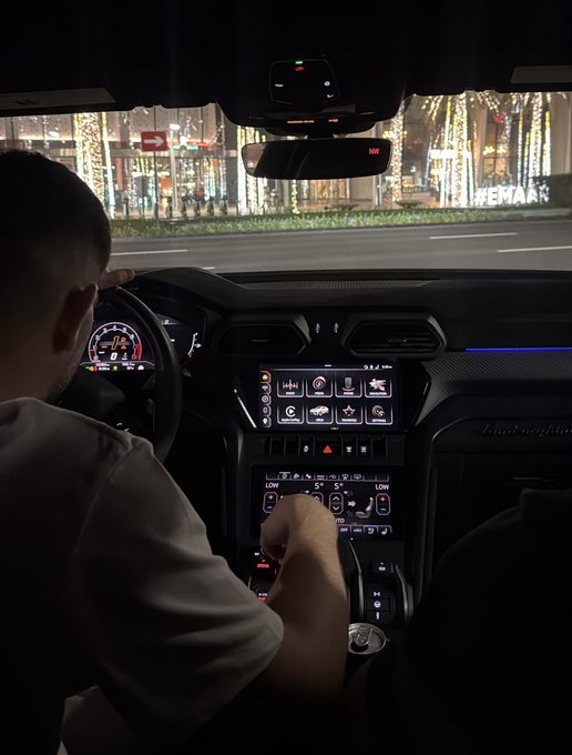 A driver sits behind the wheel of a Lamborghini at night, with the digital dashboard showing "3.1" and "5," set against a backdrop of illuminated street decorations. The image pairs with a message about valuing character and integrity over wealth or success in the crypto space.