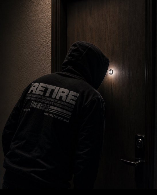 A person wearing a black hoodie with 'RETIRE' printed on the back, standing in front of a door looking through the peephole.