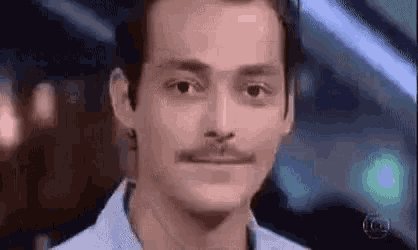 iced coffee with foam on top, a man's face with a mustache and goatee, and a blurred background of people and buildings.