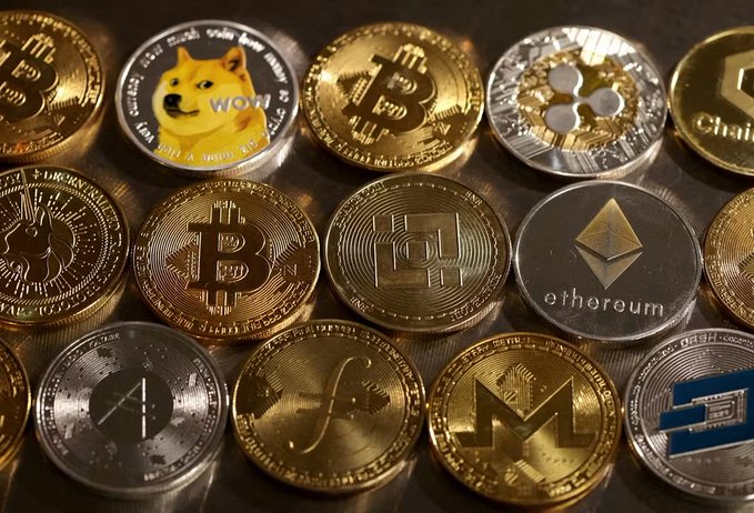 An assortment of physical representations of various cryptocurrencies, including Bitcoin, Ethereum, Dogecoin, Ripple (XRP), Monero, Tron, Chainlink, and Litecoin, arranged in a display. The image relates to the accompanying post by illustrating the diverse range of digital currencies that institutional investors like Nomura Group are now entering the market to trade through newly registered crypto asset exchange operators.