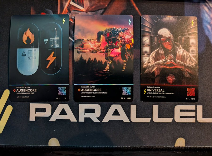 Three trading cards from the 'PARALLEL' card game displayed in protective sleeves: 'Augencore' variants for Jennifer Locke and Chris Korte, and a 'Universal' card titled 'Word Purveyor of Curiosities' for Radomir Vinkler.