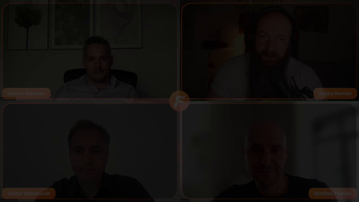 The image shows a group of four men sitting at their desks for a video conference call. They are all looking into the camera with smiles on their faces, suggesting that they are engaged in a friendly conversation or meeting. The background appears to be a plain white wall, which helps draw attention to the people and their expressions during the call.