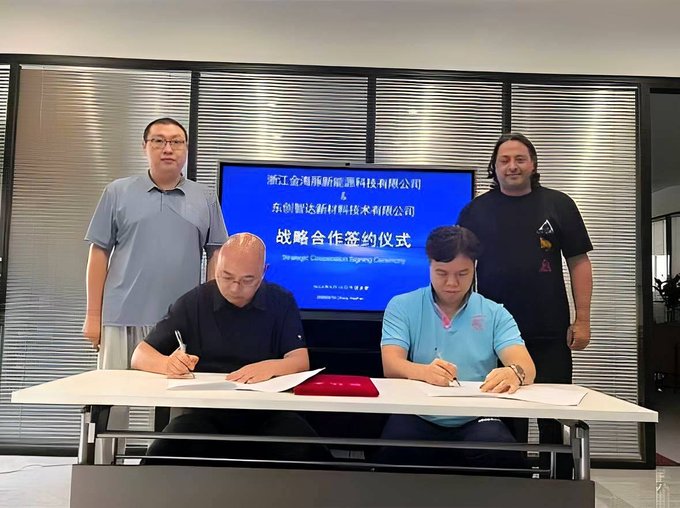 A photograph of a strategic cooperation signing ceremony between 浙江金海豚新能源科技有限公司 (Zhejiang Gold Dolphin New Energy Technology Co., Ltd.) and 东创智达新材料技术有限公司, showing four men with two seated at a signing table.