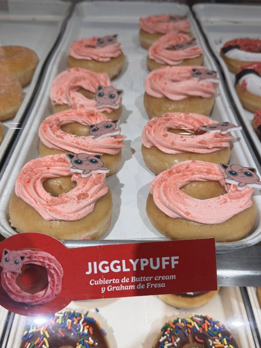 A display of donuts with pink frosting labeled 'JIGGLYPUFF' with 'Cubierta de Butter cream y Graham de Fresa' written below, decorated with Jigglypuff character cutouts from Pokémon.