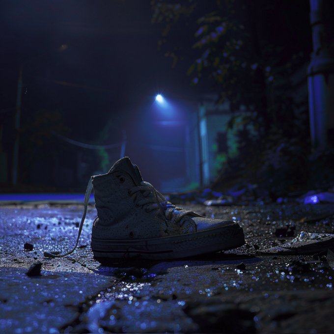 A lone white sneaker sits abandoned on a wet, debris-strewn street at night, illuminated by a distant streetlight in a moody, cinematic scene.