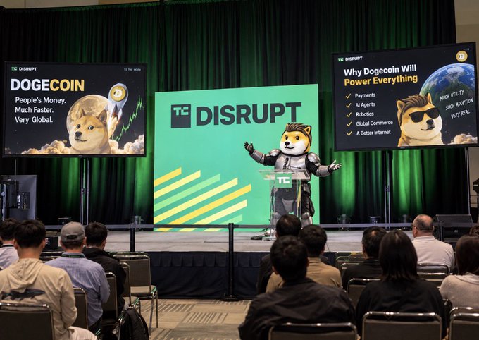 A conference stage at TC Disrupt featuring a Dogecoin presentation with the Doge mascot, titled 'DOGECOIN - People's Money. Much Faster. Very Global.' and 'Why Dogecoin Will Power Everything'.