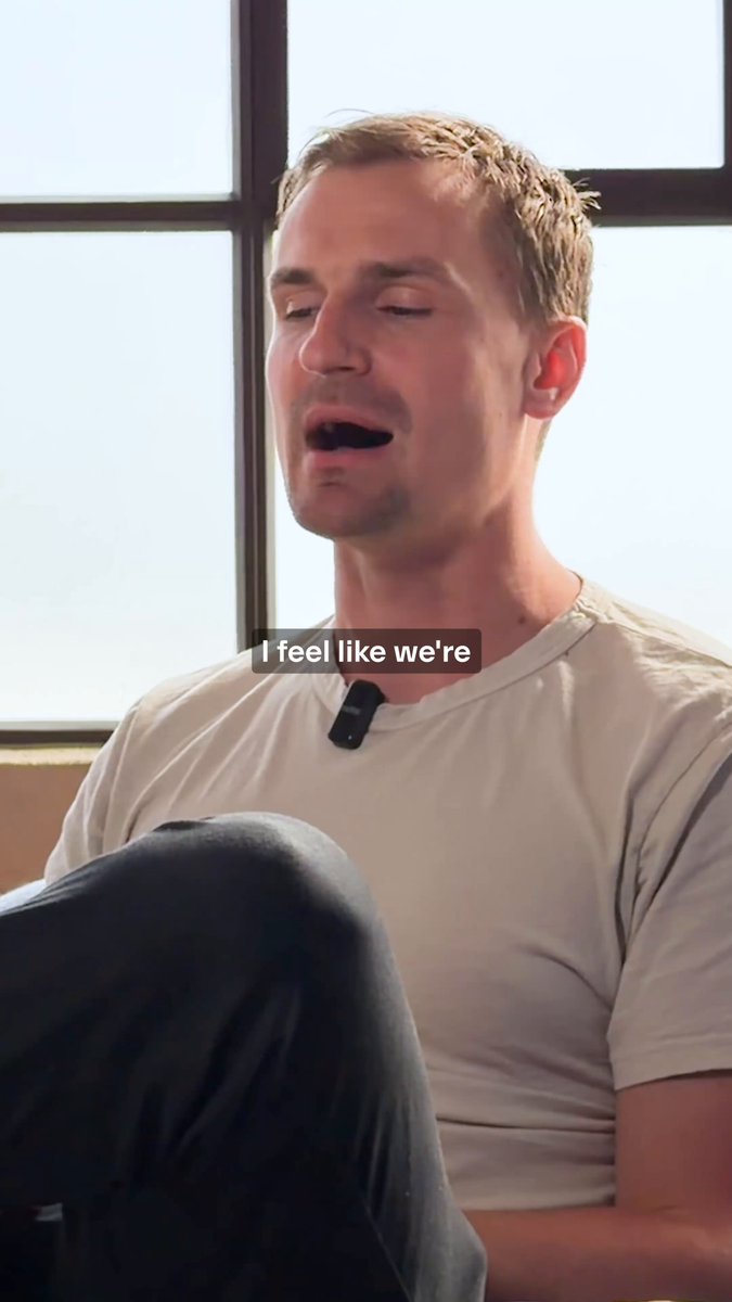 The image shows a man sitting down with his legs crossed while wearing a white shirt. The caption of the image reads "I feel like we're Base", which seems unrelated to the main subject matter, but could be interpreted as a metaphor for the idea that Base is building rails for onchain payments to be low-cost, instant, private and available everywhere.