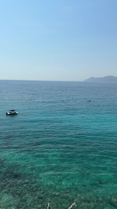 A calm turquoise sea stretches toward a hazy island, with a small boat floating offshore. The peaceful view matches the post’s announcement of taking a break until Sunday’s Live Stream, PPI data updates, and commentary on volatility.