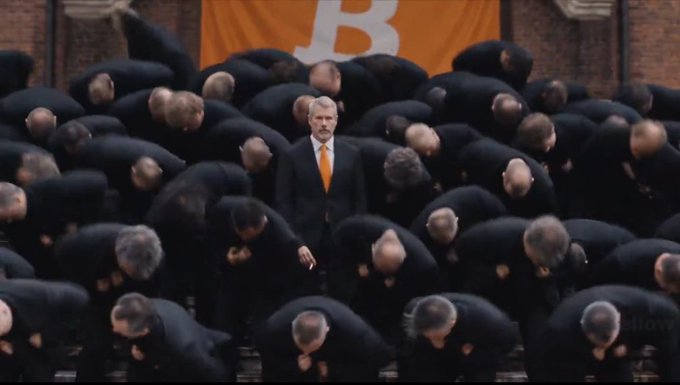 The image depicts a man in a suit standing prominently in front of a crowd of bowing men, with a large Bitcoin 'B' logo on an orange banner behind him, corresponding to the text that states '@saylor is copying @JupiterExchange' to promote $JUP.