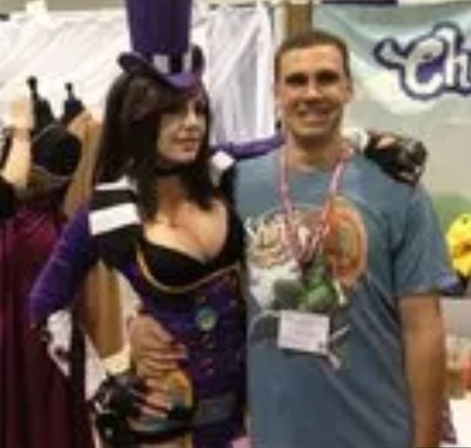 A man poses for a photo with a woman dressed as Mad Moxxi, a character from the Borderlands video game series, at what appears to be a convention booth (with partial signage visible suggesting "Cha..." in the background). The image humorously accompanies the post, as "Moxxi" sounds phonetically similar to the joke tokens "ho," "ry," "sh," "it," and "bro" listed in the post, playing on the creator's playful endorsement of the "S&P6900" meme coin.