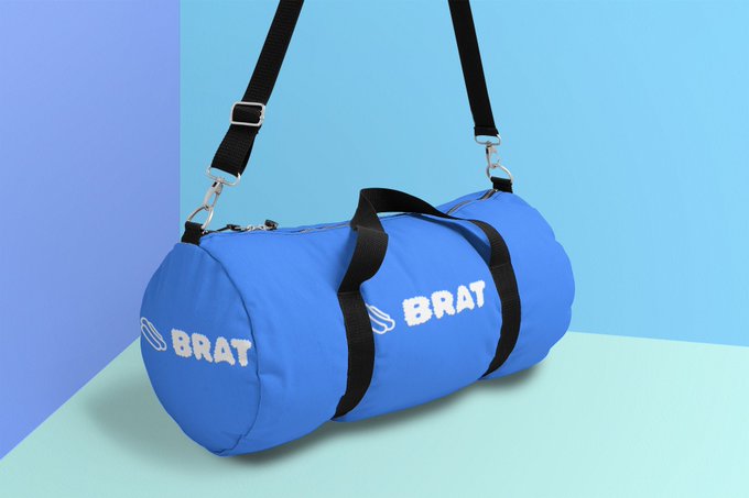 A blue cylindrical duffel bag with 'BRAT' printed in white letters on both ends, featuring black carrying straps, displayed against a blue and purple gradient background.