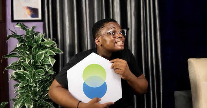 A young man wearing glasses smiles excitedly while holding up a white sign featuring the green and blue Unifi logo, likely as part of his application to the @unifi_x ambassador program mentioned in the post. The image captures his enthusiasm for joining the creator opportunity being advertised.