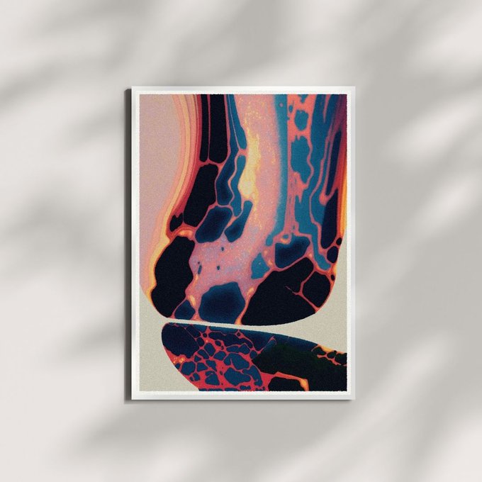 A framed piece of abstract art featuring flowing patterns in navy, orange, and pink hues hangs on a white wall with leafy shadows cast across it.